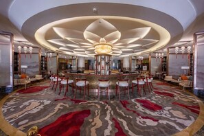 A spacious lobby with a central bar, seating area, and a large chandelier.