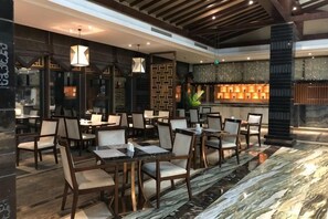 A restaurant with multiple tables and chairs, a bar area, and a decorative wall.