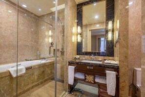 A modern bathroom with a glass shower enclosure, a marble vanity, and a large mirror.