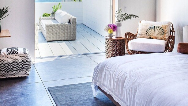 Een slaapkamer met een groot bed, een plafondventilator en uitzicht op de zee door een geopende deur.