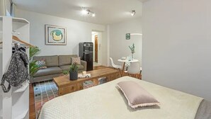 Een knus woongedeelte met een bed, een bank, een eettafel en een kitchenette.