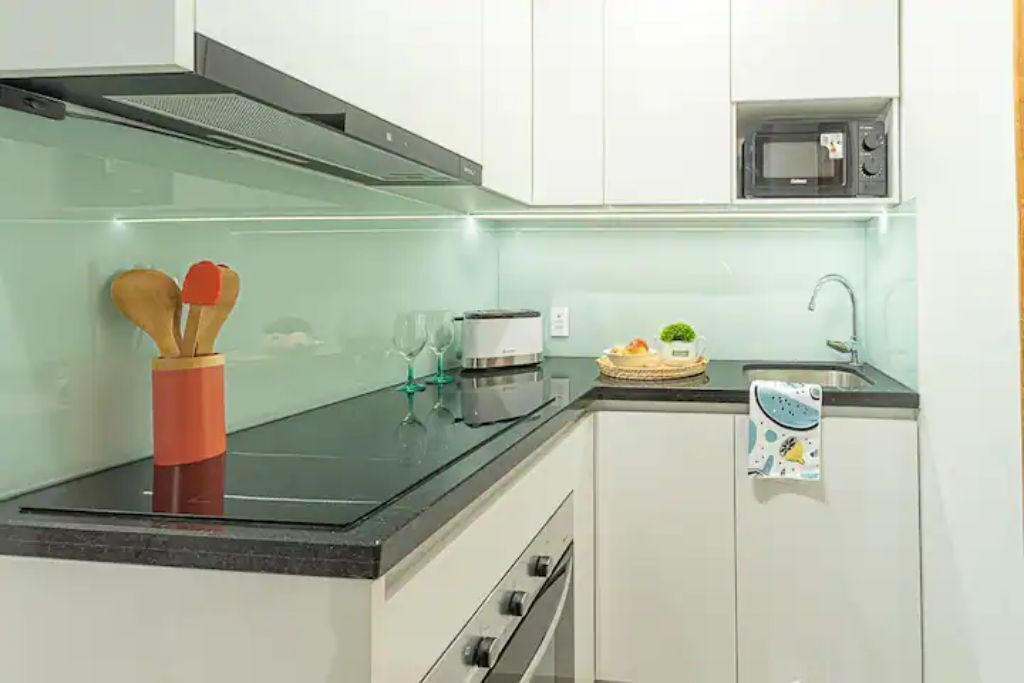 A modern kitchen with white cabinets, a black countertop, a microwave, and a toaster.
