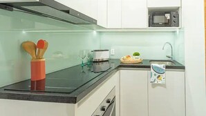 Een moderne keuken met witte kastjes, een zwart aanrecht, een magnetron en een broodrooster.