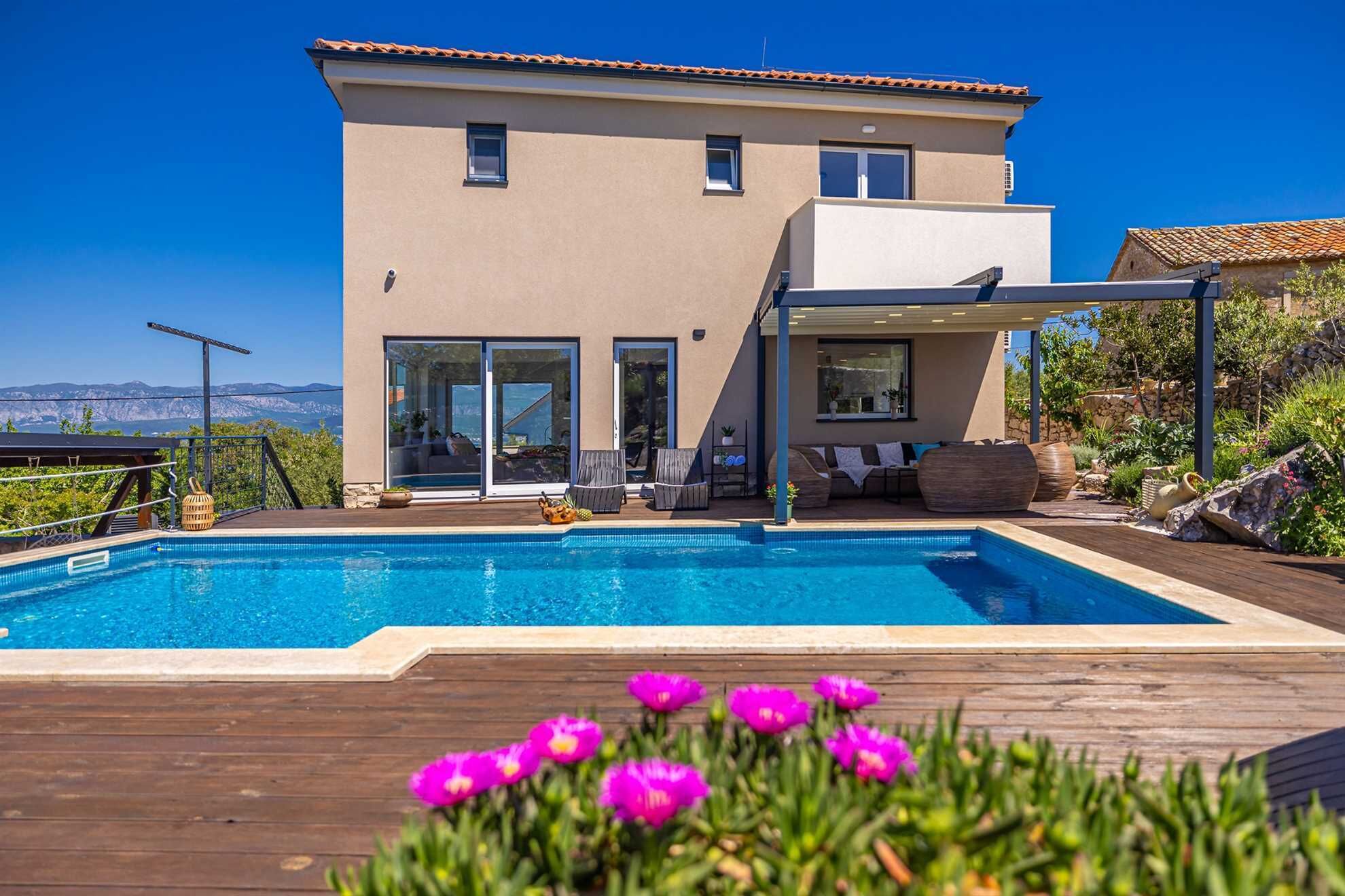 A modern house with a swimming pool, large windows, and a view of the mountains.