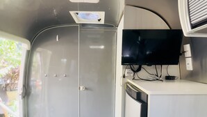 A compact kitchen with a built-in TV, a small seating area, and a door leading to another room. - Airstream Escape + Pool + Fenced Yard (Austin)