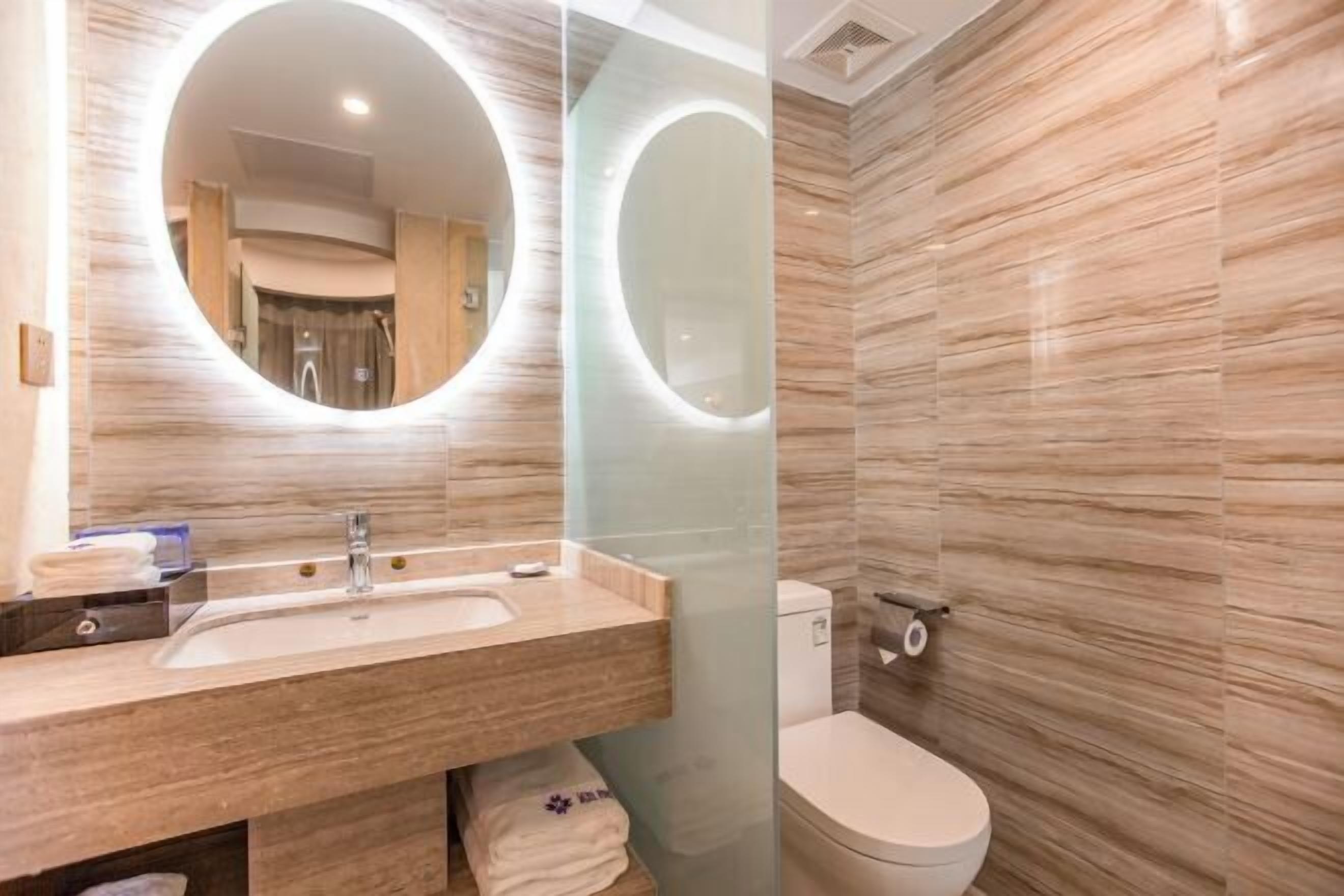 Une salle de bain moderne avec un grand miroir, un lavabo et des toilettes.