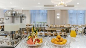 Un’area colazione in hotel con un buffet, inclusi frutta fresca e un angolo dedicato alle bevande.