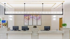 Una reception con due monitor, un orologio e una pianta.