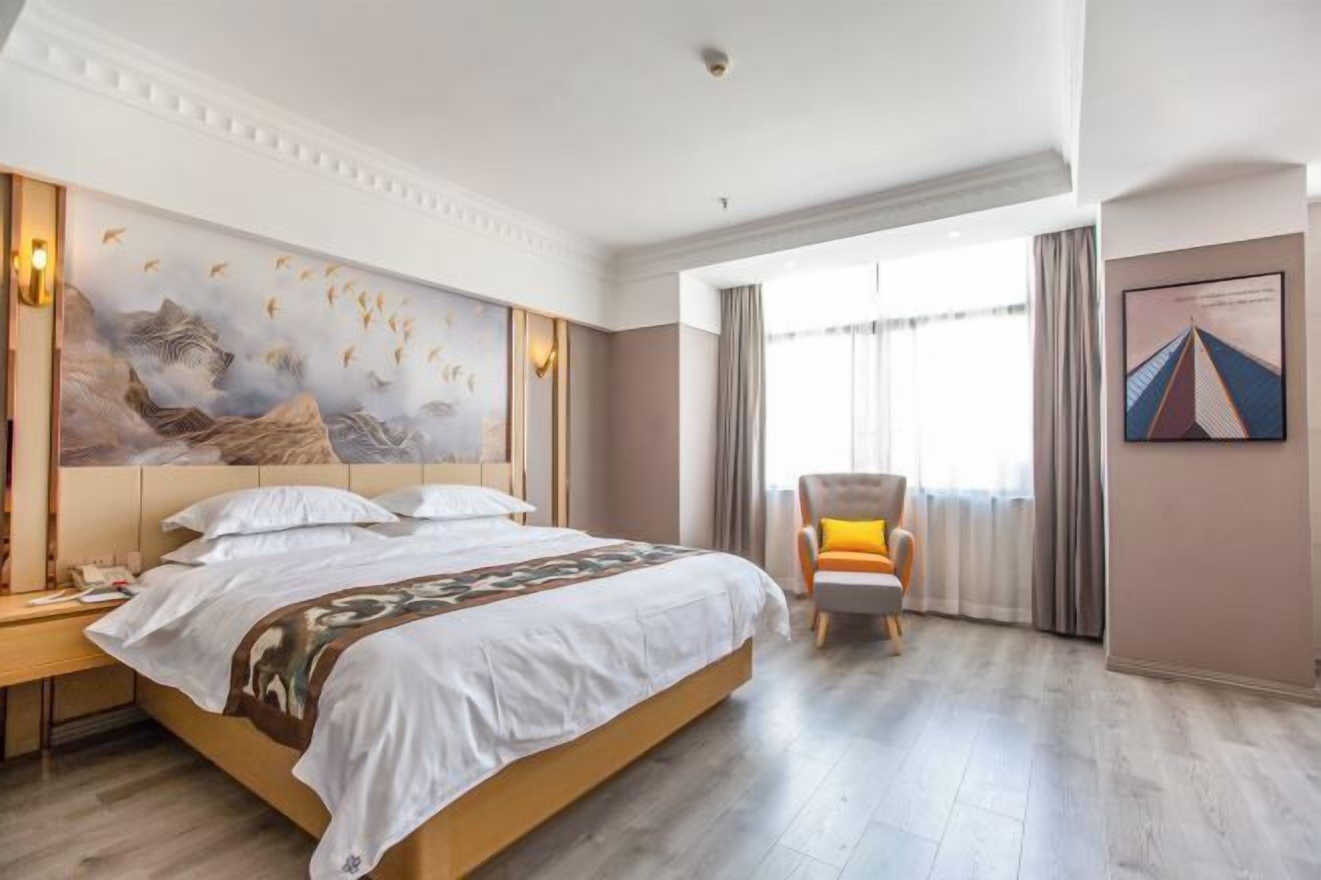 Habitación de hotel con una cama grande, una silla, un escritorio y un cuadro en la pared.