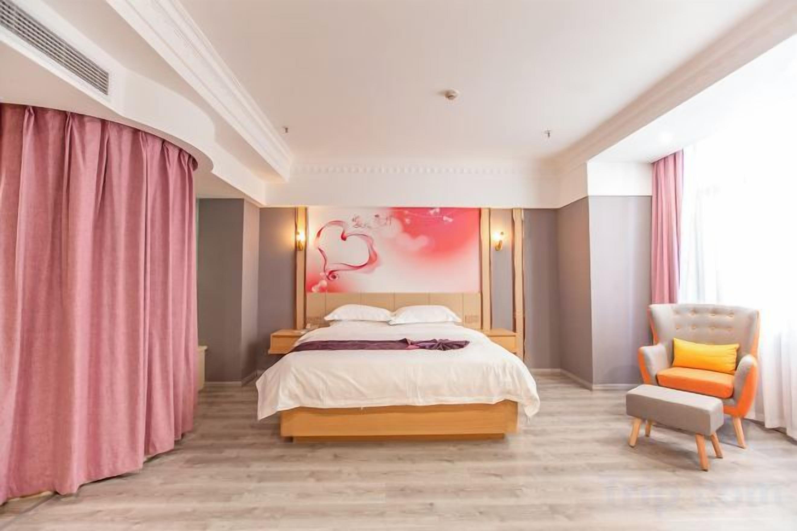 Ett hotellrum med en stor säng, en stol och en vägg med en lampa.