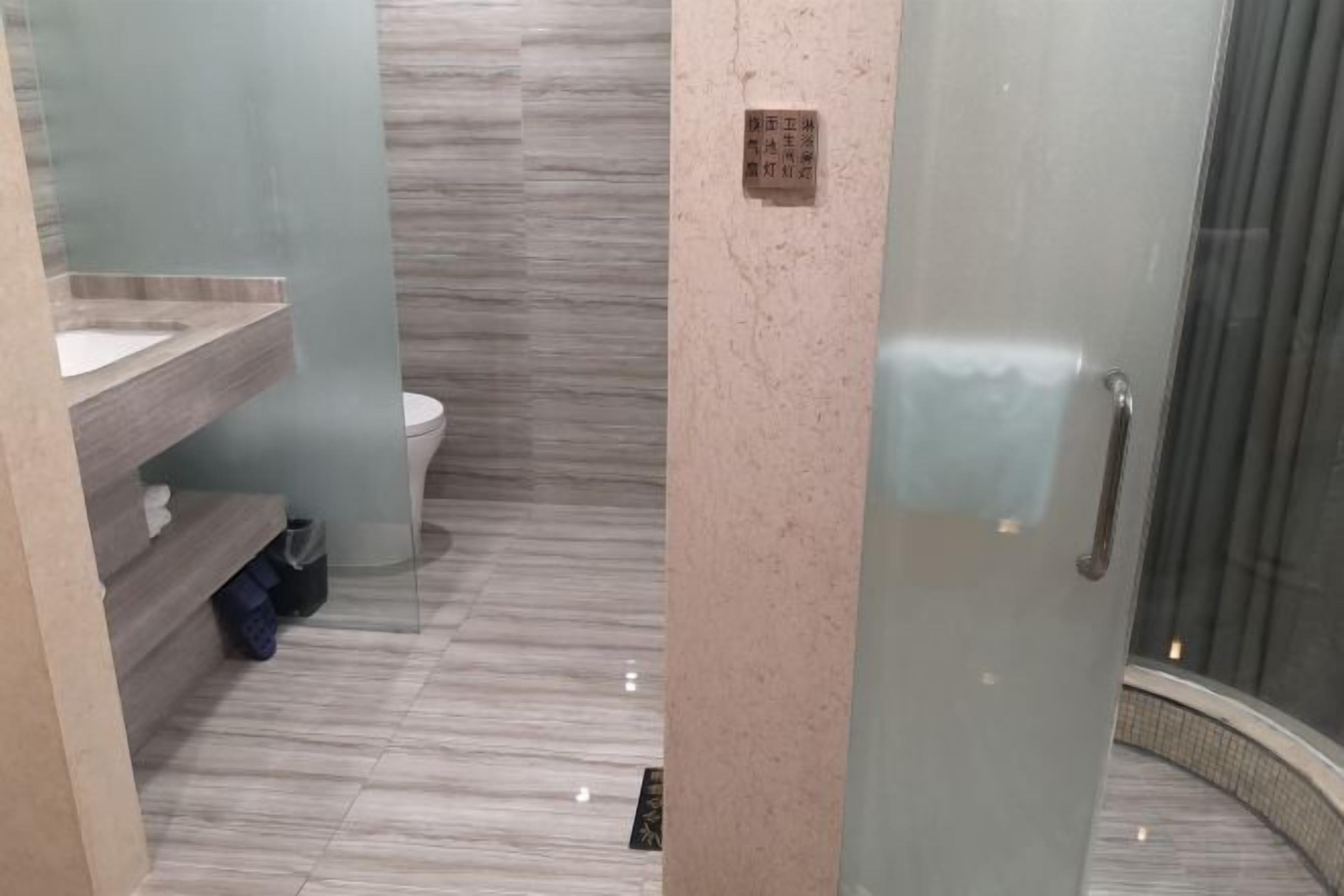 Casa de banho com piso de mármore, cabine de chuveiro em vidro e pia com bancada.
