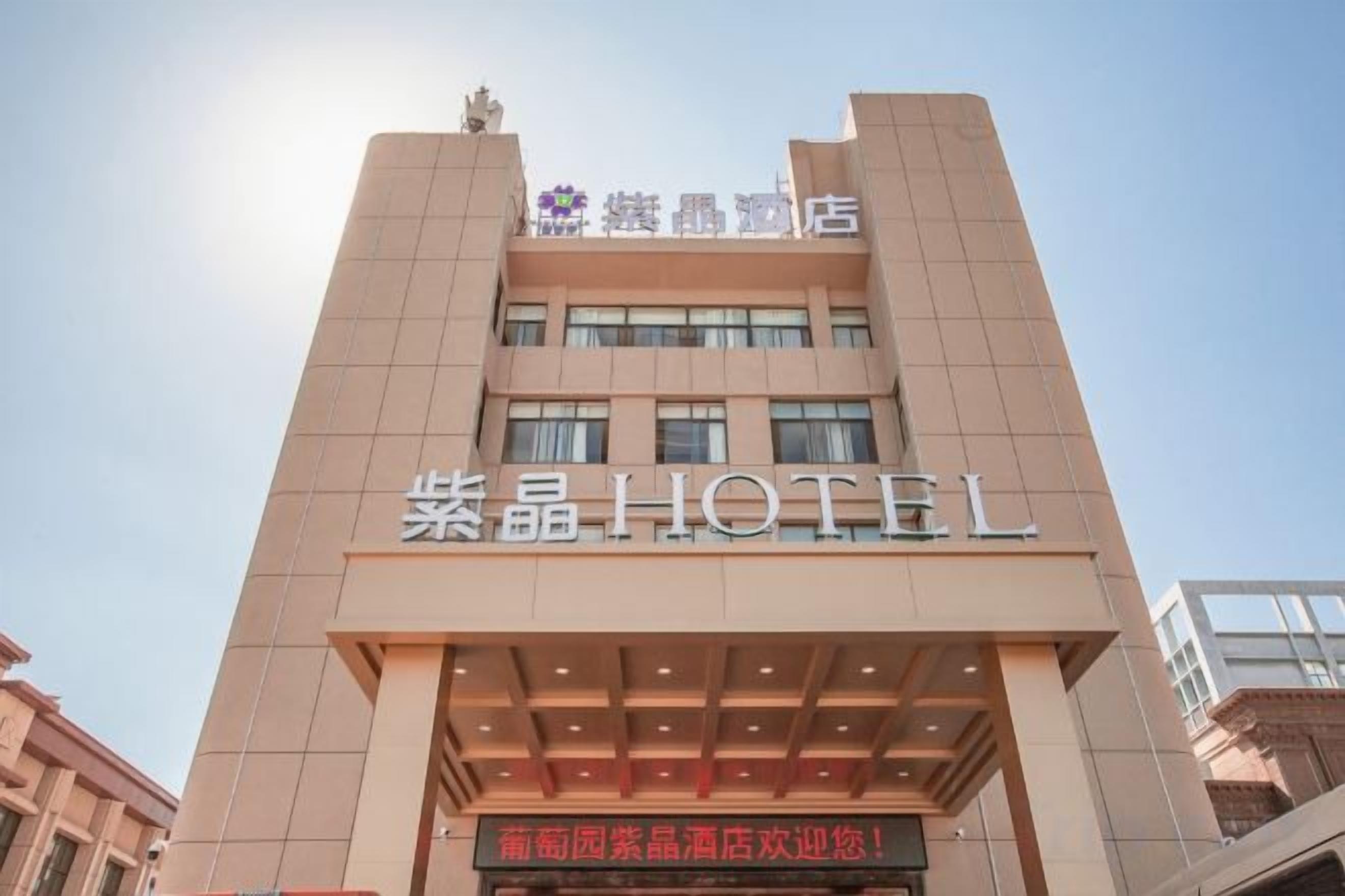 A hotel building with a prominent sign reading '紫晶HOTEL'.