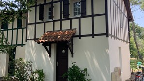 Una casa tradicional de entramado de madera con una puerta marrón oscuro, un pequeño jardín y una bicicleta estacionada afuera.