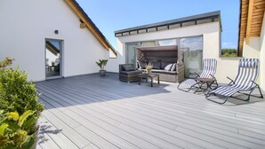 A modern outdoor patio with a built-in seating area, a table, and lounge chairs. - Beautiful vacation apartment. Top floor near the beach & quiet location to relax (Gaski)
