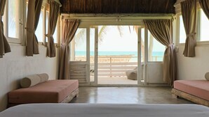 A room with two beds, a wooden bench, and a view of the beach. - Tuup Tulum (Tulum)