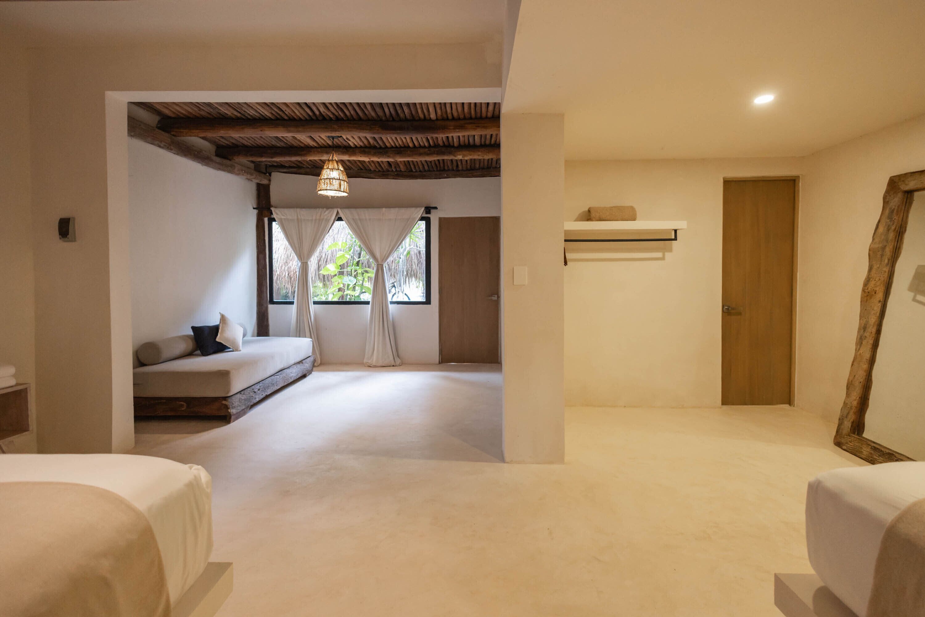 Un dormitorio amplio con una cama grande, un banco empotrado y un techo con vigas a la vista.
