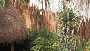 A swimming pool with two striped lounge chairs and potted plants. - Tuup Tulum (Tulum)