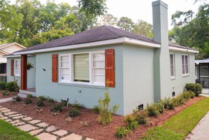 Une maison de plain-pied avec une cheminée, un porche à l’avant et un petit jardin.