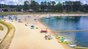 A beach with kayaks, umbrellas, and a water fountain. - Fort Benning family stay · Fenced yard + fire pit (Columbus)