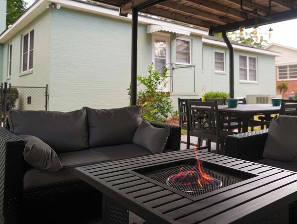 An outdoor seating area with a fire pit, a sofa, and a table. - Fort Benning family stay · Fenced yard + fire pit (Columbus)