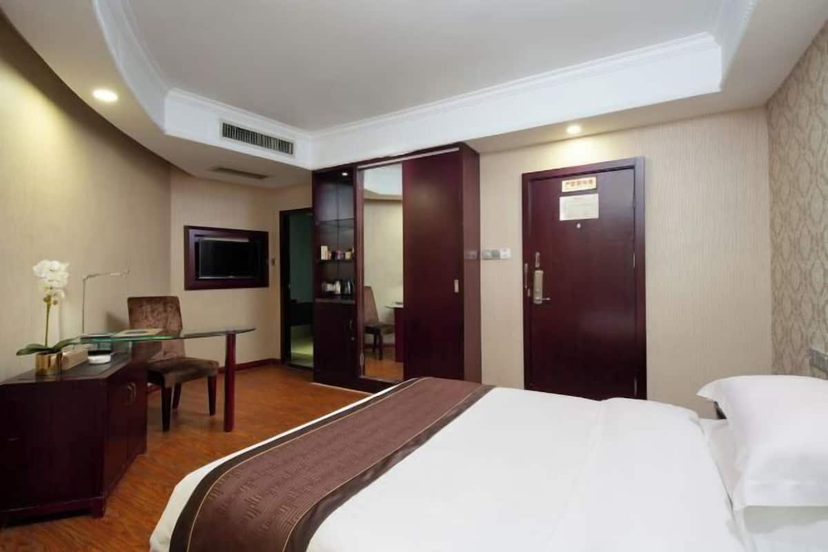 Ein Hotelzimmer mit Bett, Schreibtisch, Stuhl, Kleiderschrank und Fernseher.