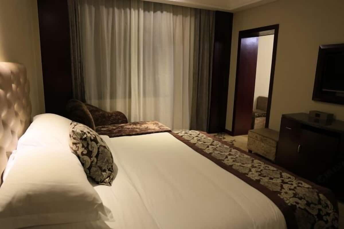 Ein Hotelzimmer mit einem großen Bett, einem Nachttisch, einer Kommode und einem Spiegel.