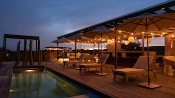Una piscina al aire libre, sombrillas, sillones reclinables de piscina