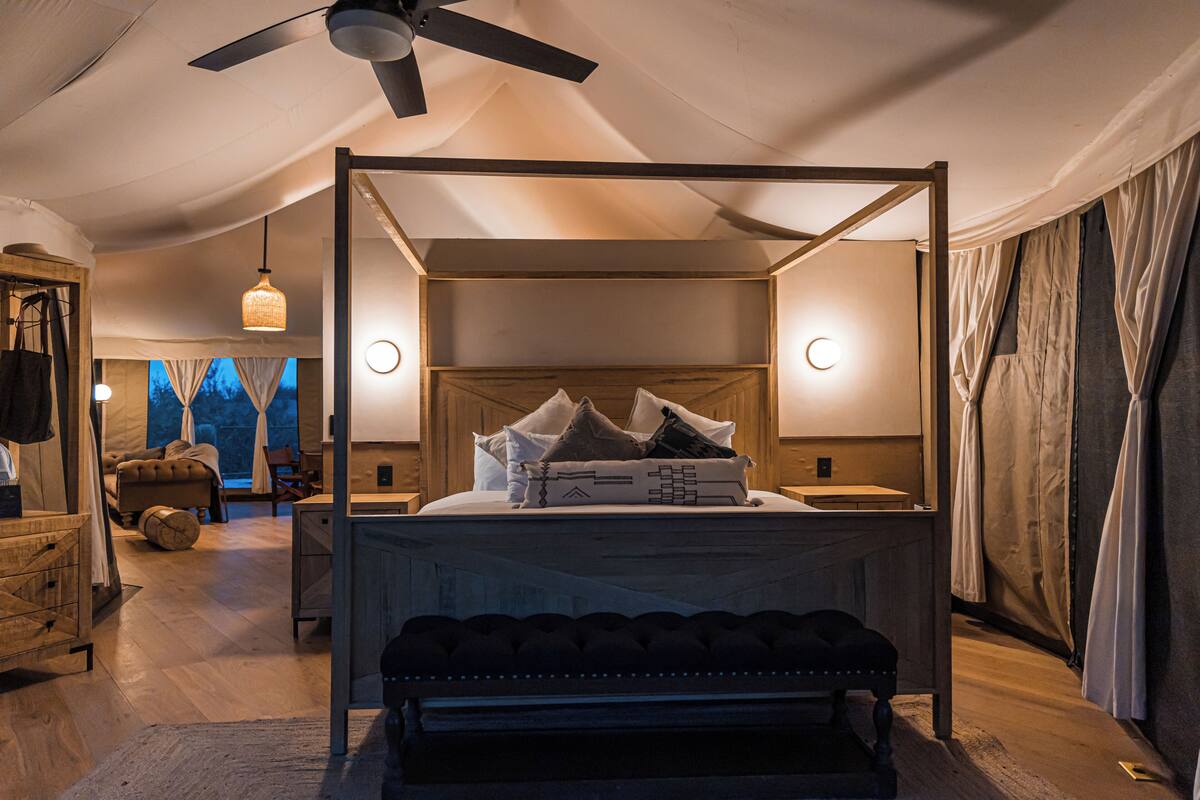 A four-poster bed with a headboard, bedside tables, and a bench.