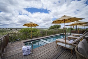 Una piscina al aire libre, sombrillas, tumbonas