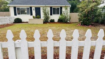 A single-story house with a white picket fence in the foreground.