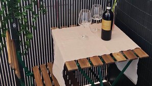 A table set with wine glasses and a bottle, surrounded by wooden benches and a vertical garden. - Small and cozy studio apartment in the center of Florence (FIRENZE)