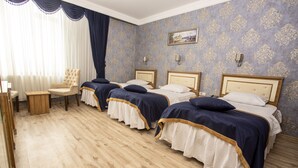 A hotel room with four beds, a wooden floor, a chair, and a painting on the wall. - GLOBAL OTEL (Mus)