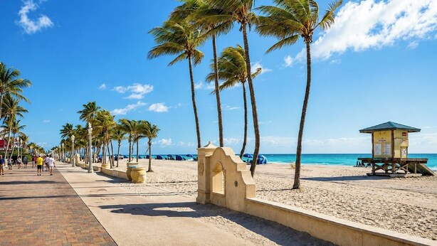 A beach with palm trees, a lifeguard tower, and a paved walkway. - Oceanfront Stylish Studio with Rooftop Pool (miami)