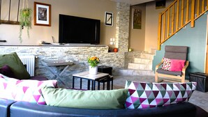 Un salon avec un canapé, une table basse, un téléviseur et un mur en pierre.