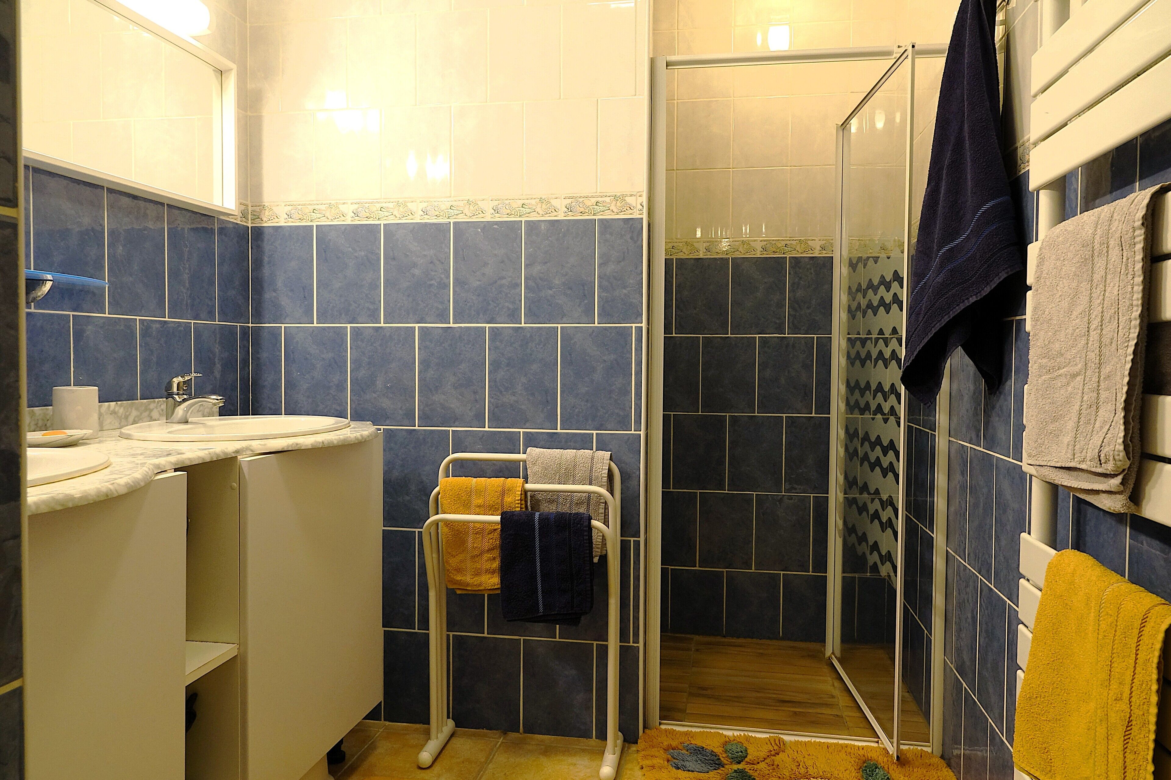 Un bany amb un lavabo, mirall, barra de tovalloles i zona de dutxa.