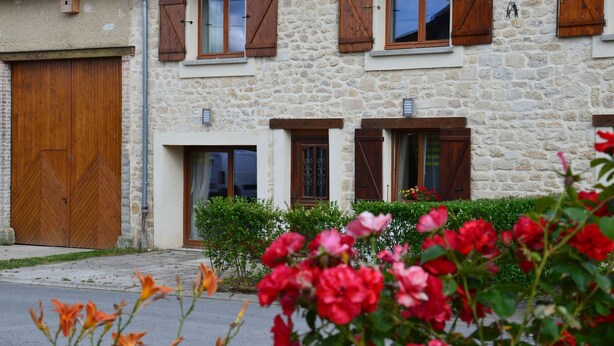 Un bâtiment en pierre avec des volets en bois, une grande porte en bois et une petite fenêtre.