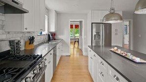 A modern kitchen with white cabinets, stainless steel appliances, and a wooden floor.