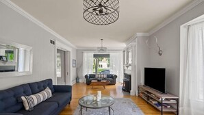 A living room with a dark blue sofa, a glass coffee table, a fireplace, a television, and a bookshelf.