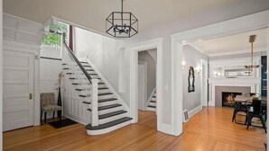 A spacious interior with a wooden staircase, white walls, and a fireplace.