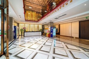 A hotel lobby with a reception desk, a large mirror, and a patterned floor. - Niu De Cao Hotel (Shenzhou)