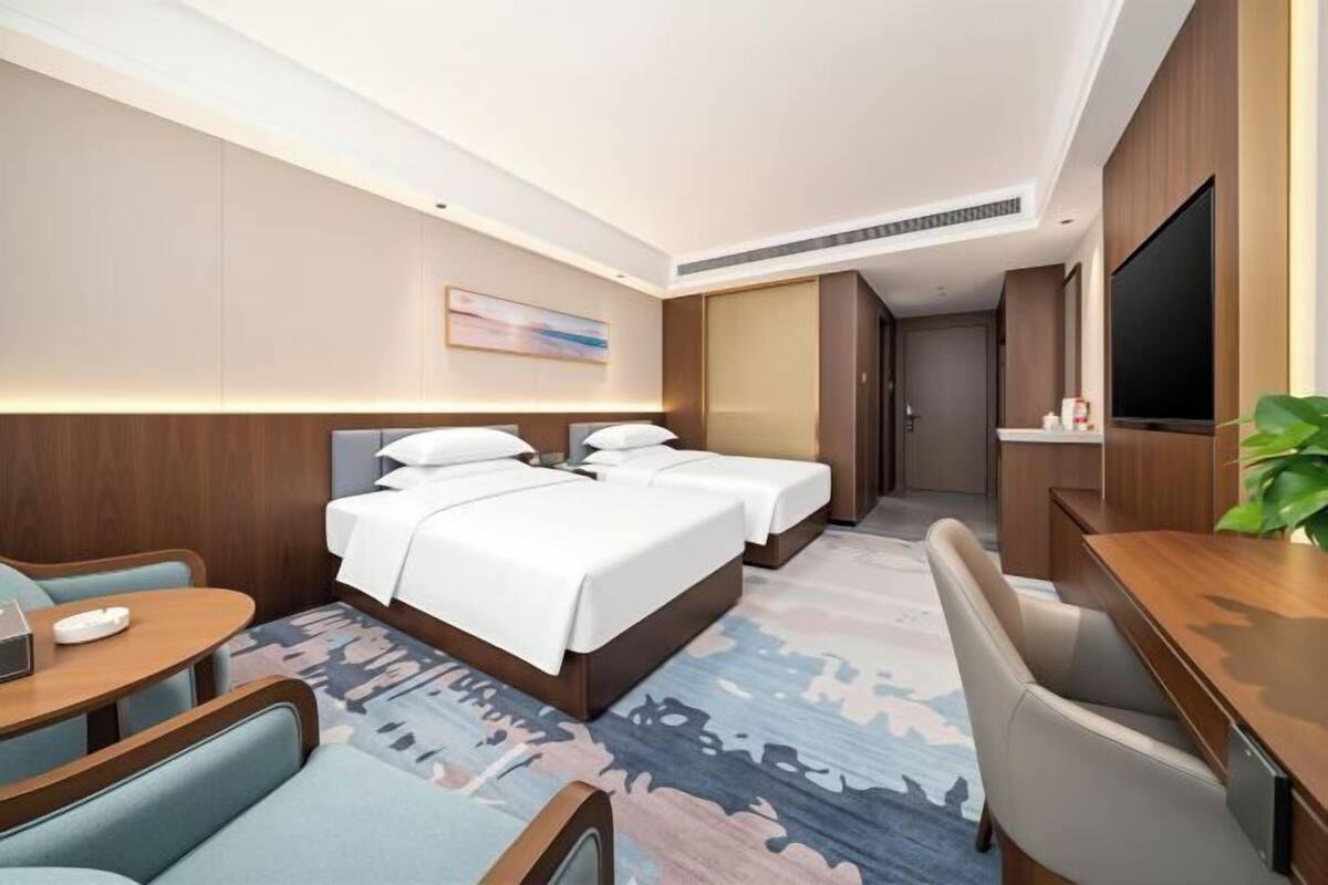 Une chambre d’hôtel avec un lit, un bureau, une chaise, une télévision et un tableau au mur.
