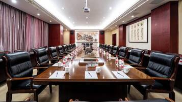 Un salón de conferencias con una larga mesa, varias sillas y un proyector.