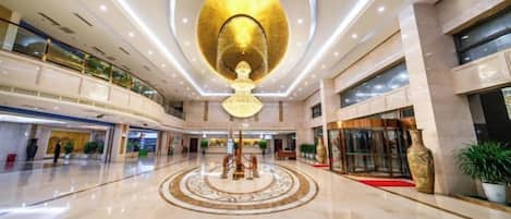 A spacious lobby with a central circular design, a large chandelier, and multiple floors with balconies.