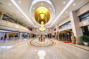 A spacious lobby with a central circular design, a large chandelier, and multiple floors with balconies.