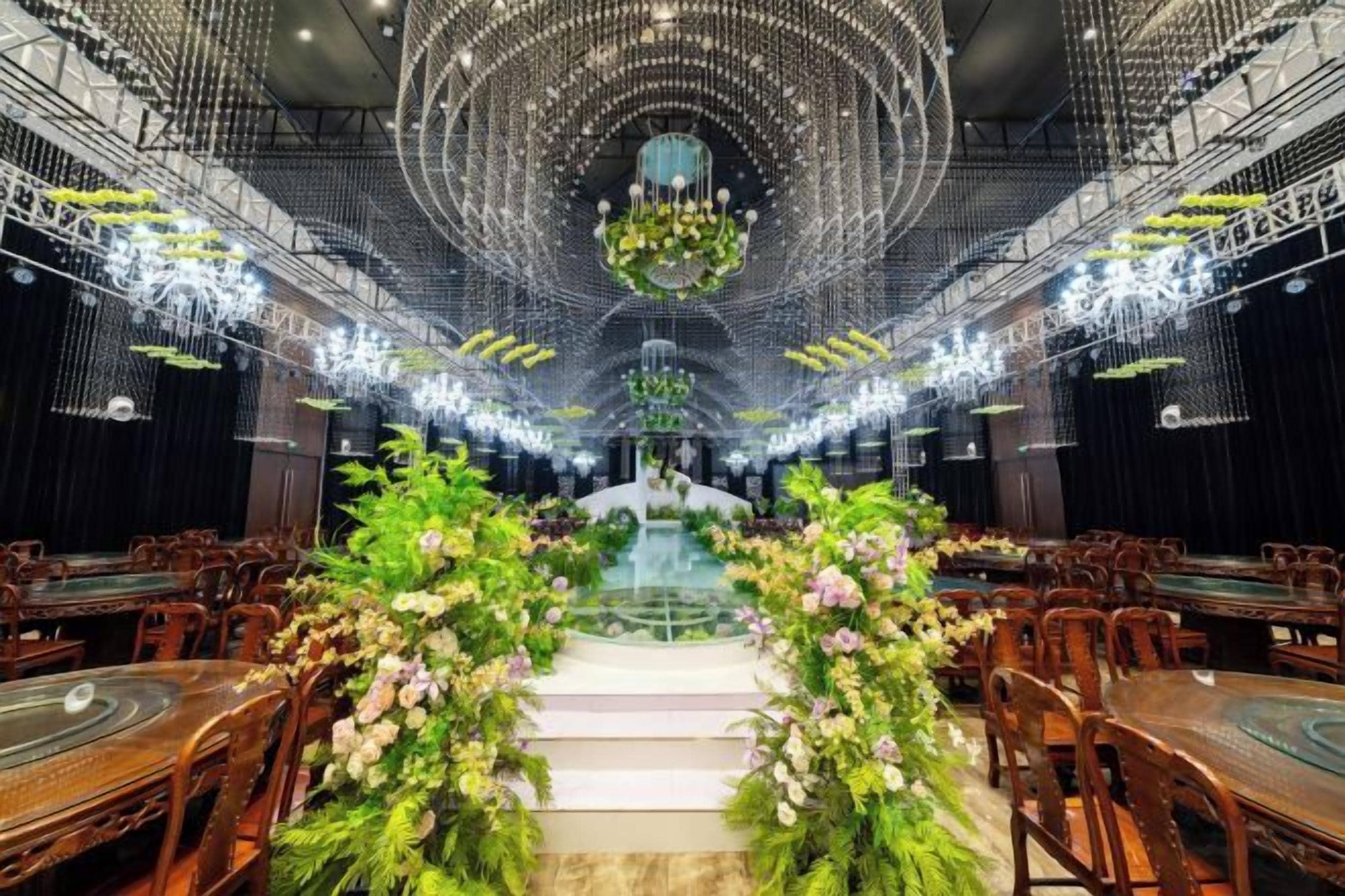 A banquet hall with tiered seating, a central stage, and a chandelier.