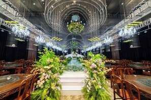 A banquet hall with tiered seating, a central stage, and a chandelier.
