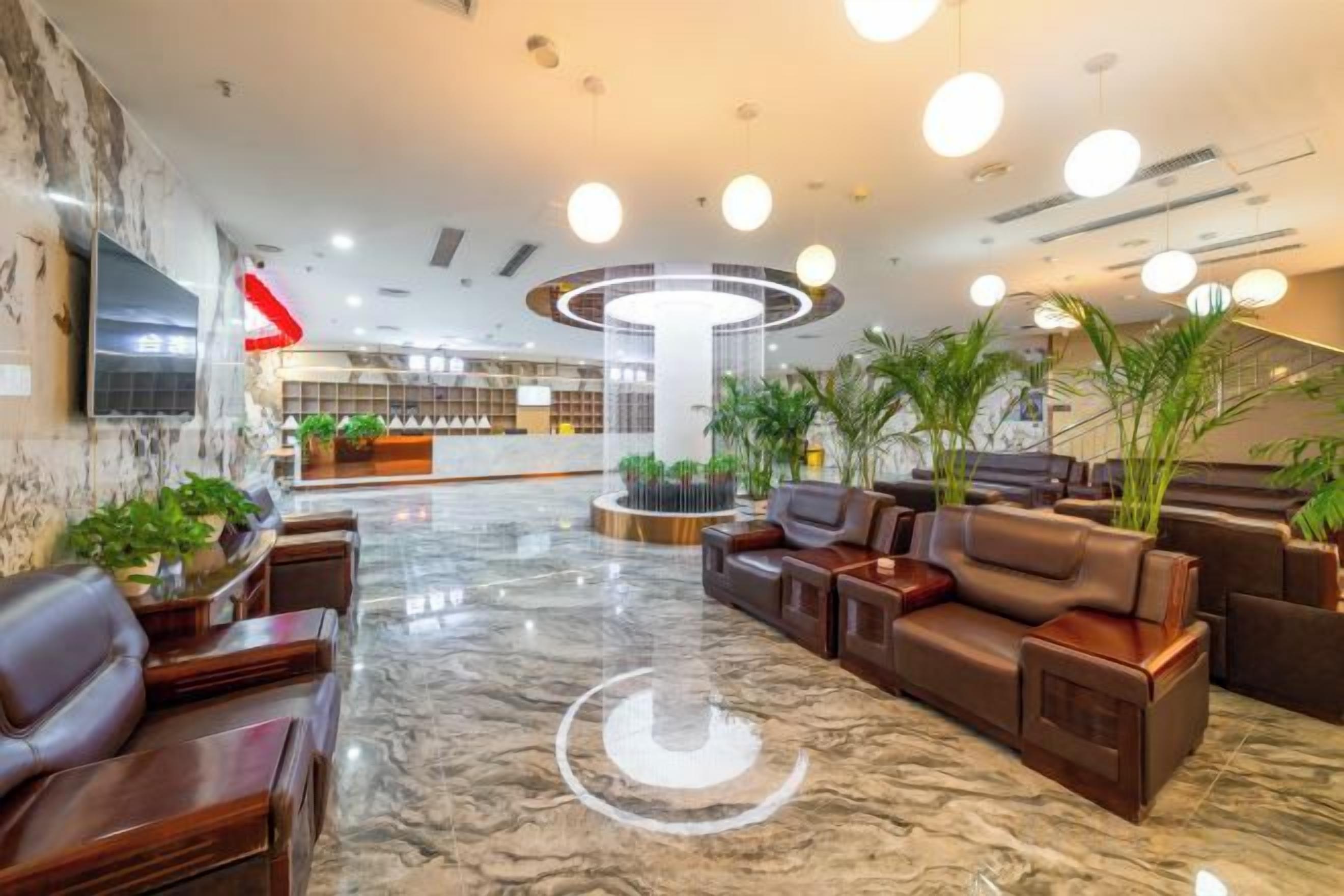 A hotel lobby with a reception desk, seating area, and a large circular light fixture.