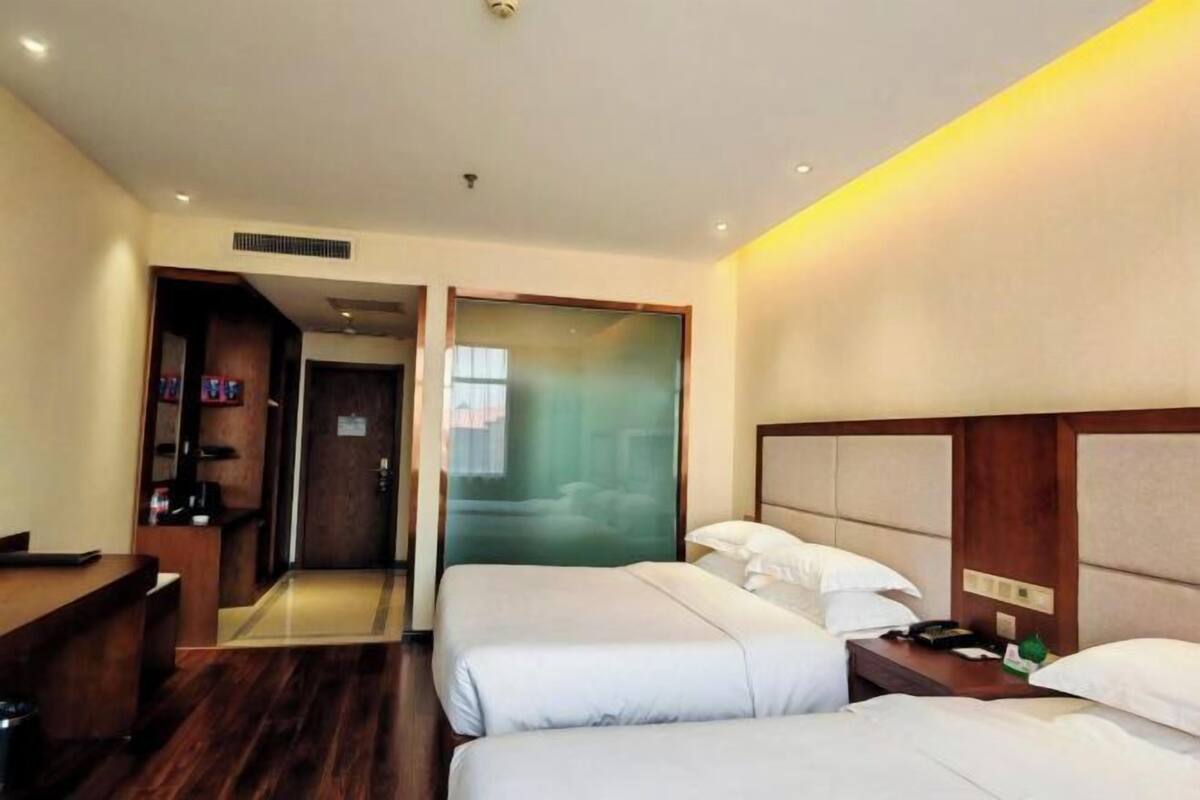 Une chambre d’hôtel avec deux lits, un bureau et un miroir.