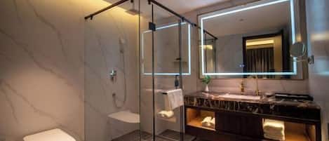 A modern bathroom with a glass-enclosed shower, a marble vanity, and a large mirror.