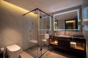 A modern bathroom with a glass-enclosed shower, a marble vanity, and a large mirror.